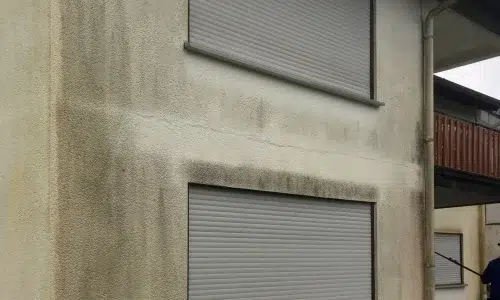 Dunkle Streifen und Flecken auf einer Fassade